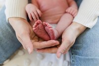 A glossy photograph taken by Studio Roscher of a mother holding her newborn's feet in Richmond, VA