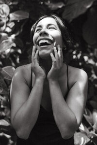 A mother laughs and holds her face gazing into the sunshine during her maternity photos in houston texas