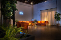 Modern corporate event lounge with orange seating, greenery and custom lighting designed by Stylish Events by Lisa in Phoenix Arizona
