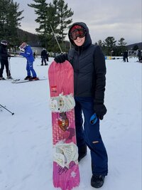 Emily, the photographer of Studio Roscher, smiling with her pink snowboard