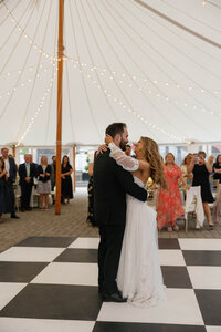 Couple shares first dance in tent with black and white checkered floors at Steven's Osgood Estate in Massachusettes