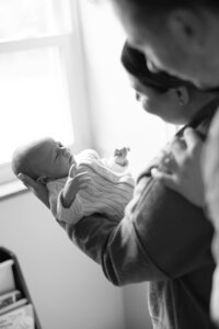 black and white image of mother holding and looking at her newborn baby