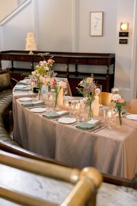 Elegantly set wedding reception table with candlelight, sage napkins, and blush florals inside a warmly lit DC venue