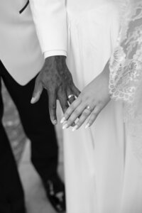 bride and groom holding their hands together and showing their wedding rings