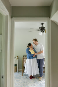 mother and father holding baby in the their nursery