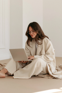 u6512682322_a_woman_with_long_brown_hair_sits_on_a_light_beig_8f2d9fac-5b38-4c28-abf5-9e91c4a98904_2