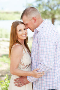 Man leaning into his fiancee while she smiles at engagement session in Colorado.