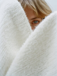 Powder - Child_s face peeking through white knitted fabric material - TVS