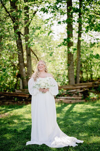 Bride holding a bouquet of flowers on a farm while taking wedding photos.
