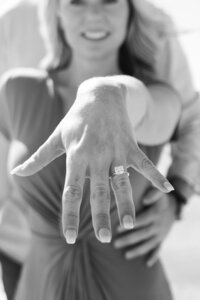 A glossy photograph taken by Studio Roscher of a happy engaged couple with a ring outside in a park in Richmond, VA