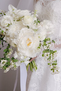 Close-up of a white bridal bouquet with peonies, ranunculus, and flowering branches
