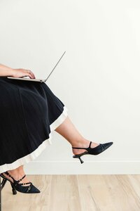 Travel advisor with a laptop on her lap while showing off her black heels