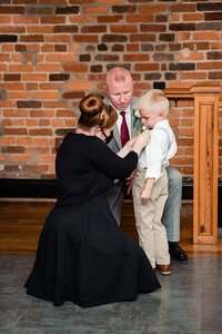 Wedding planner with Weddings & Events by Raina pins boutonniere onto ring bearer