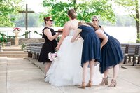 Wedding planners with Weddings & Events by Raina assist the bride with bustling her wedding dress