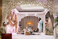 Hindu wedding ceremony underneath the gold filigree mandap decorated with gold drapery and purple uplighting