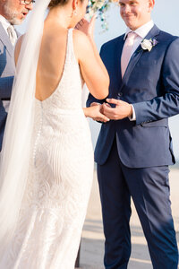 Bride wiping away a tear as she holds hands with her groom during their wedding ceremony at Addy Sea in Bethany Beach, Delaware.