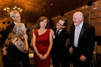 A classic event photo of a birthday party for a woman in a red dress with her guests all smiling at her in Richmond, VA