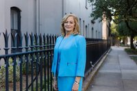A classic professional portrait taken by Studio Roscher of a female professional smiling in a blue suit in a park