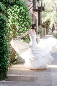 Bride twirling in a flowing wedding gown along a sunlit, ivy-covered street in Baltimore, Maryland.