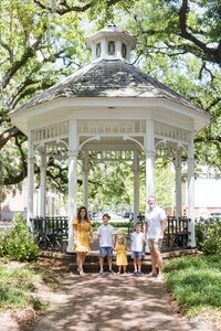 A glossy photograph taken by Studio Roscher of a happy family outside in a gazebo park in Savannah, GA
