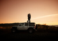 cCouple standing on top of a Jeep during sunset for an adventurous engagement session with Angie Rich Photography in San Antonio.