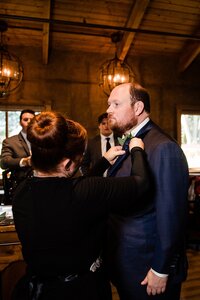 Wedding planner with Weddings & Events by Raina pins on the groom's boutonniere