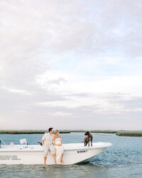 A couple sitting on their boat with their dog in the backdrop during their maternity photography session at Wrightsville Beach, North Carolina