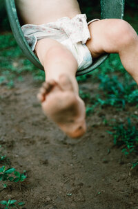 A childs dirty foot while swinging outside during a family photo session in Houston TX