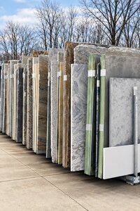 Outdoor collection of marble, granite, quartz, and natural-stone remnants in assorted colors and patterns.