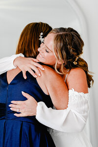 Bride and mother of the bride sharing a hug while getting ready on a wedding day.