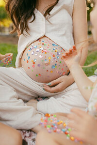 A mothers pregnant belly covered in glitter stickers for her maternity photo session in houston texas