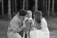 mother and father standing with young child during family photos