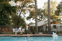 A family enjoys an evening by their backyard pool during their at home family photo session near houston texas