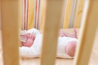 A glossy photograph taken by Studio Roscher of a newborn sleeping in a crib in Richmond, VA