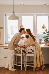 Couple sharing a kiss with their children nearby