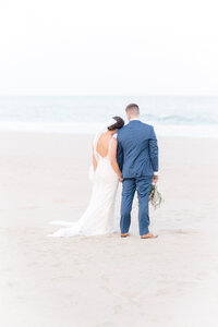 Bride and groom standing together at the water’s edge during a romantic coastal Delaware beach wedding.