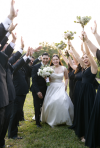 Bride and groom celebrating with their closest friends during an outdoor wedding in San Antonio as guests cheer with bouquets, capturing authentic joy and candid wedding moments.