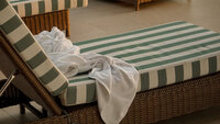 Striped hotel lounge chair with a white towel draped across it