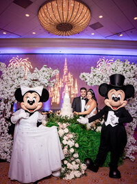 bride and groom cutting wedding cake with Mickey and Minnie Mouse