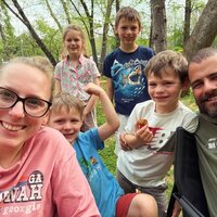 Emily, the photographer of Studio Roscher, smiling with her husband and kids while camping