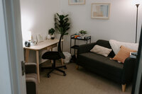 therapy office with a desk and chair with a couch and pillows