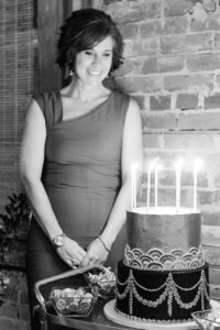 A black and white photo of a woman in a red dress with a candlelit cake for her birthday party in Richmond, VA