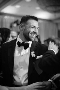 Groom laughs candidly with guests during the wedding reception