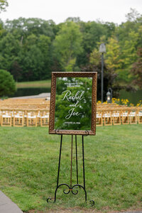 wedding ceremony with wooden chairs and mirror-style welcome sign