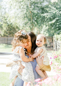 A mother and her babies cuddling in close in their backyard during an in home family photography session in Wilmington, North Carolina