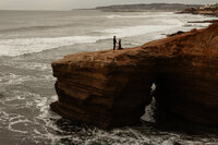 Couple standing on a coastal cliff during a romantic proposal captured by Angie Rich Photography, a San Antonio proposal photographer.