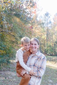 A glossy photograph taken by Studio Roscher of a happy mother and son outside in a park in Richmond, VA