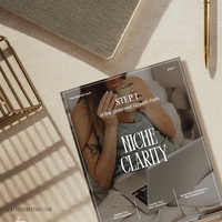 Close up of the Niche Clarity workbook against a beige background with gold desk accessories.