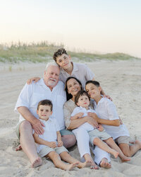 A mom, dad, and two toddler boys playing and laughing on the beach during their sunset family photography session at Wrightsville Beach, North Carolina