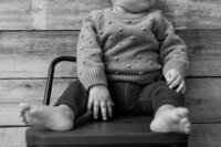 A glossy photograph taken by Studio Roscher of a newborn in a sweater and jeans in Richmond, VA